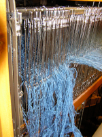 Wide shot of metal heddles and warp threads showing a large number of heddles